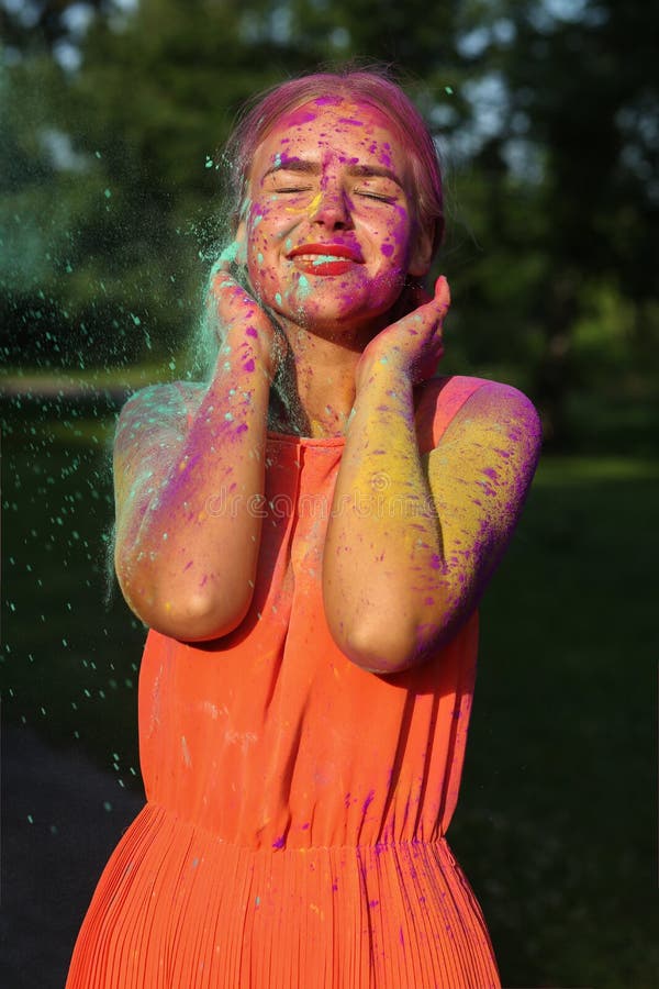 Excited blonde model posing covered with a colorful dry paint at. Excited blonde woman posing covered with a colorful dry paint at the park royalty free stock photography